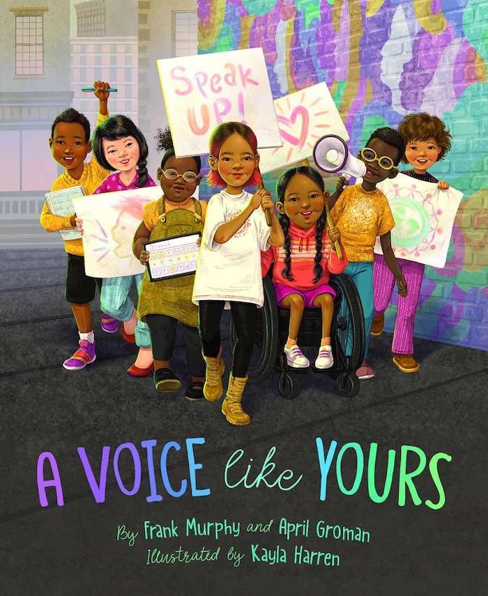 Six diverse children stand together, holding protest signs with encouraging messages like "Speak Up!" One child uses a wheelchair. They all look joyful and confident—a powerful addition to picture books about communication. Title: "A Voice Like Yours.